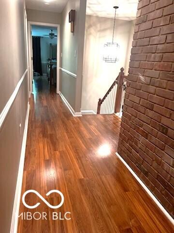 8310 Fall Creek Rd, Indianapolis, IN 46256 - hall featuring an upstairs landing, wood finished floors, and brick wall