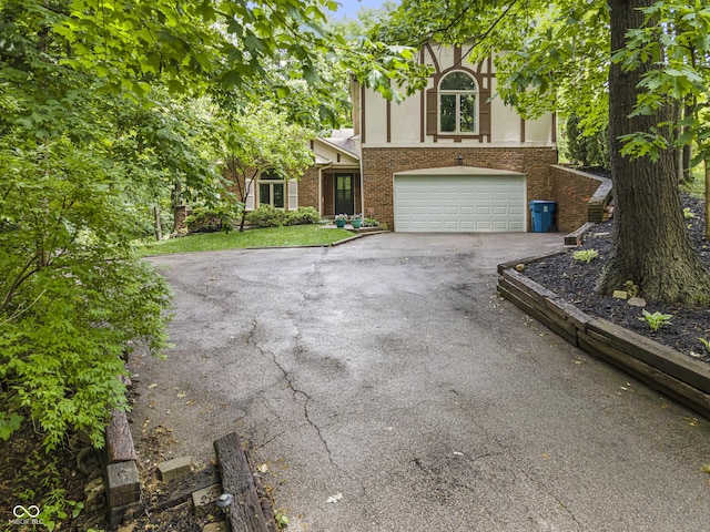 8310 Fall Creek Rd, Indianapolis, IN 46256 - english style home featuring asphalt driveway, an attached garage, brick siding, and stucco siding