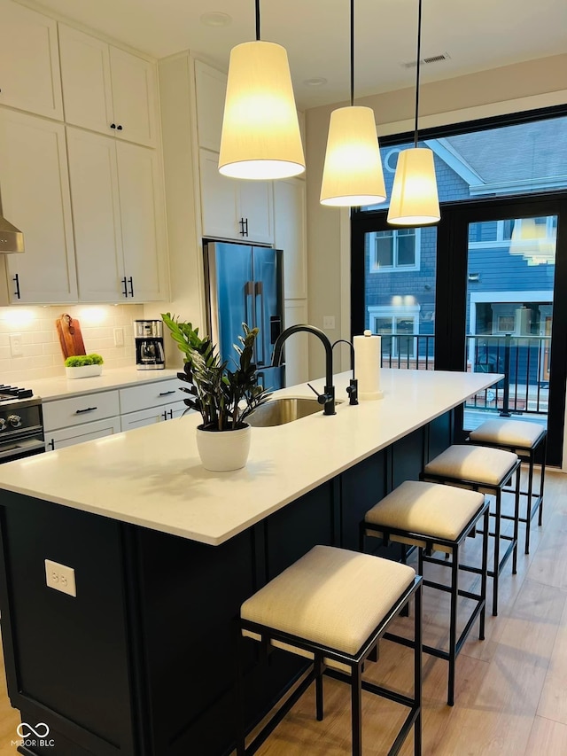 711 E 16th St, Indianapolis, IN 46202 - kitchen featuring high end refrigerator, light wood finished floors, white cabinetry, light countertops, and a kitchen island with sink