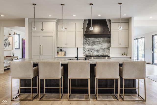 3549 W 131st St, Carmel, IN 46032 - kitchen with premium range hood, a center island with sink, recessed lighting, tasteful backsplash, and light wood-type flooring