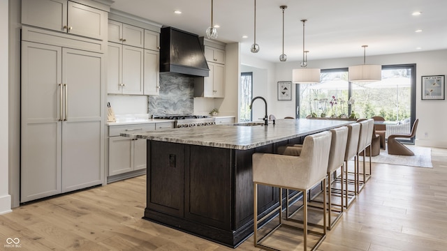 3549 W 131st St, Carmel, IN 46032 - kitchen with paneled fridge, premium range hood, light wood finished floors, a kitchen island with sink, and decorative backsplash