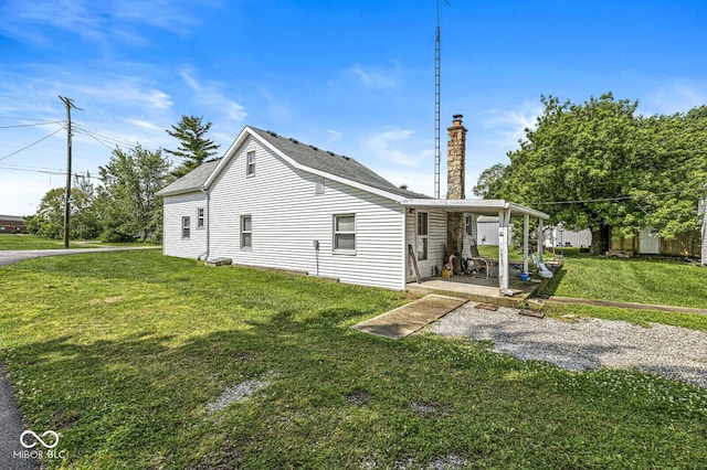 9290 Vine St, Manilla, IN 46150 - view of home's exterior featuring a chimney, a lawn, a patio, and a shingled roof