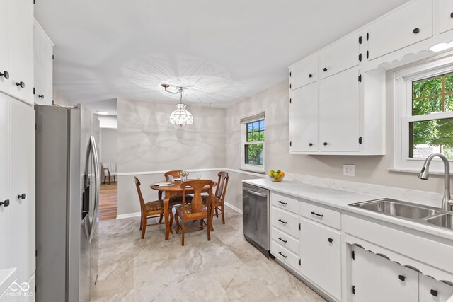 1010 Maple St, Greenwood, IN 46142 - kitchen featuring appliances with stainless steel finishes, a chandelier, light countertops, white cabinets, and hanging light fixtures
