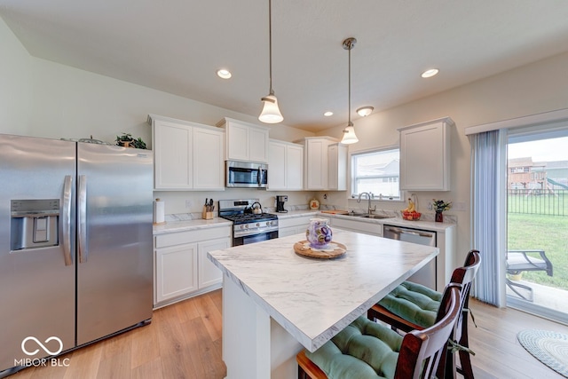 59 Manchester Dr, Trafalgar, IN 46181 - kitchen with stainless steel appliances, a sink, a breakfast bar area, light countertops, and light wood-style floors