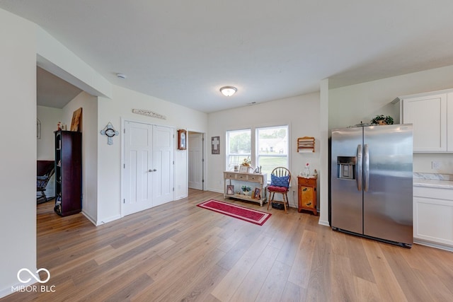 59 Manchester Dr, Trafalgar, IN 46181 - kitchen featuring stainless steel fridge, light wood-style flooring, white cabinetry, light countertops, and baseboards