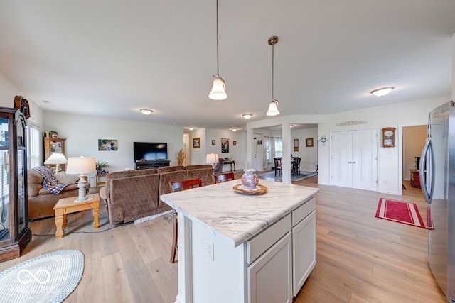 59 Manchester Dr, Trafalgar, IN 46181 - kitchen with freestanding refrigerator, open floor plan, a kitchen island, light wood-style flooring, and light countertops