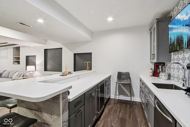 1345 Lewiston Dr, Westfield, IN 46074 - kitchen featuring stainless steel dishwasher, a peninsula, light countertops, a kitchen breakfast bar, and dark wood-style floors