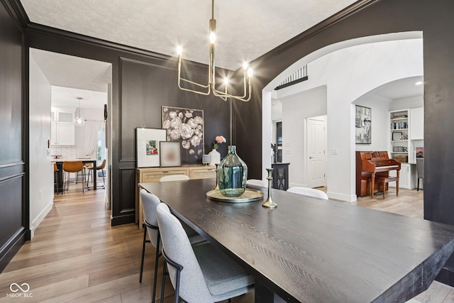 1345 Lewiston Dr, Westfield, IN 46074 - dining space featuring a chandelier, crown molding, light wood-type flooring, and arched walkways