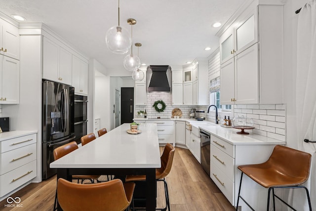 1345 Lewiston Dr, Westfield, IN 46074 - kitchen featuring black appliances, a breakfast bar, premium range hood, tasteful backsplash, and white cabinetry