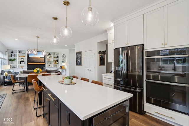 1345 Lewiston Dr, Westfield, IN 46074 - kitchen with stainless steel appliances, ornamental molding, wood finished floors, light countertops, and a kitchen island