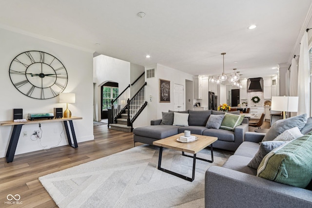 1345 Lewiston Dr, Westfield, IN 46074 - living room featuring stairway, wood finished floors, crown molding, recessed lighting, and arched walkways