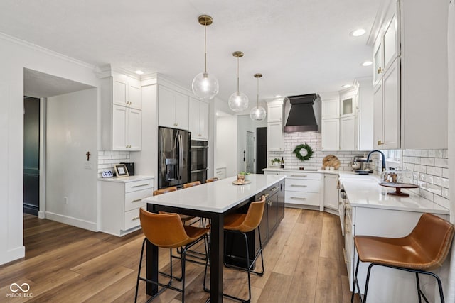 1345 Lewiston Dr, Westfield, IN 46074 - kitchen featuring premium range hood, refrigerator with ice dispenser, a kitchen island, a breakfast bar area, and light wood-type flooring