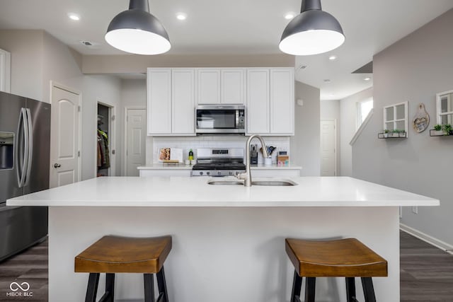 14110 Bay Willow Dr, Fishers, IN 46037 - kitchen featuring stainless steel appliances, dark wood finished floors, tasteful backsplash, an island with sink, and white cabinets