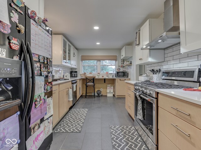 1504 Mcclure Rd, Columbus, IN 47201 - kitchen with stainless steel appliances, wall chimney exhaust hood, tasteful backsplash, tile patterned floors, and light countertops