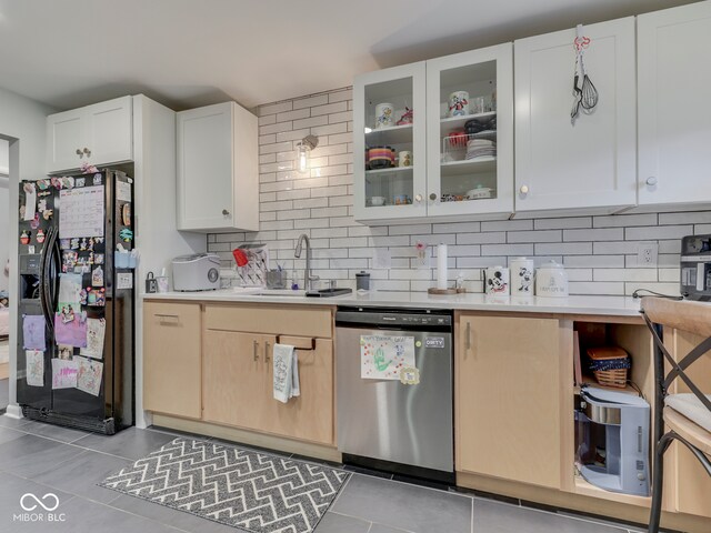 1504 Mcclure Rd, Columbus, IN 47201 - kitchen featuring stainless steel dishwasher, black fridge with ice dispenser, a sink, light tile patterned flooring, and light countertops