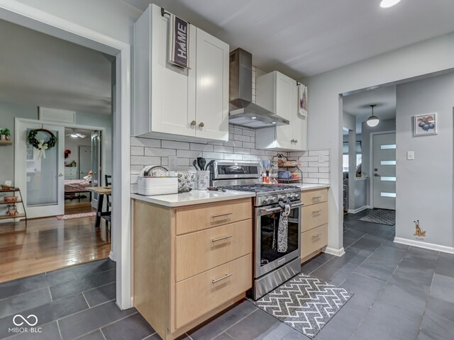 1504 Mcclure Rd, Columbus, IN 47201 - kitchen with gas range, wall chimney exhaust hood, light countertops, dark tile patterned floors, and tasteful backsplash