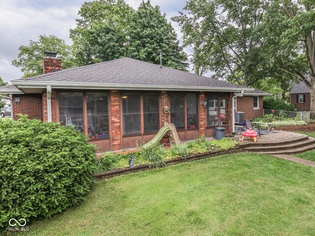 1504 Mcclure Rd, Columbus, IN 47201 - view of front of house featuring brick siding, a chimney, a sunroom, and a shingled roof