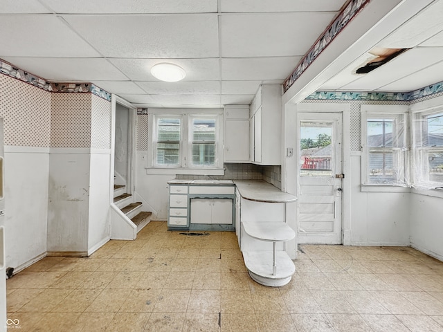 4709 E New York St, Indianapolis, IN 46201 - below grade area featuring a paneled ceiling, stairway, and light floors