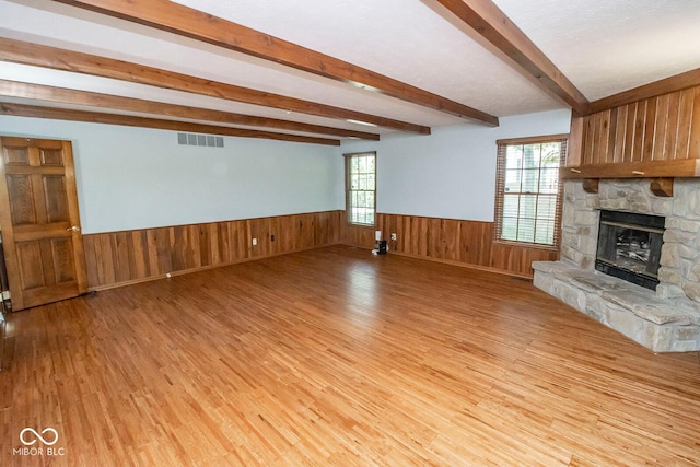 5530 Shawnee Trail S Drive, Indianapolis, IN 46220 - unfurnished living room with light wood finished floors, beam ceiling, a wainscoted wall, a stone fireplace, and wooden walls