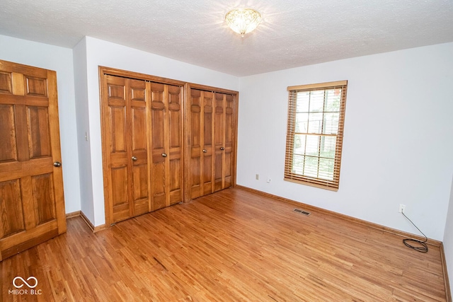 5530 Shawnee Trail S Drive, Indianapolis, IN 46220 - unfurnished bedroom with light wood-style floors, two closets, and a textured ceiling