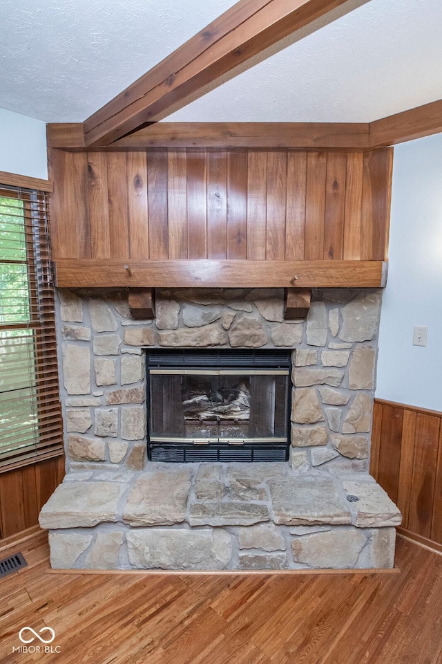 5530 Shawnee Trail S Drive, Indianapolis, IN 46220 - detailed view of a stone fireplace, wooden walls, wood finished floors, a wainscoted wall, and a textured ceiling
