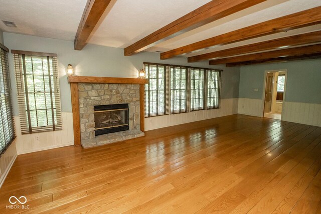 5530 Shawnee Trail S Drive, Indianapolis, IN 46220 - unfurnished living room featuring hardwood / wood-style flooring, wainscoting, a stone fireplace, beamed ceiling, and plenty of natural light