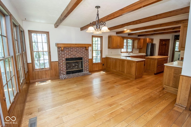 5530 Shawnee Trail S Drive, Indianapolis, IN 46220 - kitchen featuring brown cabinets, light wood finished floors, a peninsula, light countertops, and a fireplace