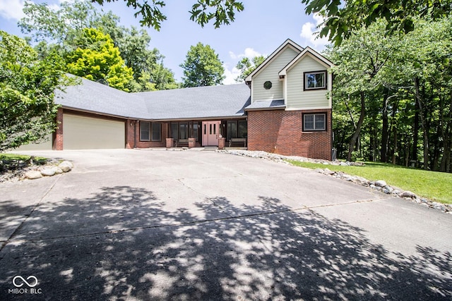 5530 Shawnee Trail S Drive, Indianapolis, IN 46220 - view of front of house featuring brick siding, an attached garage, driveway, and a sunroom