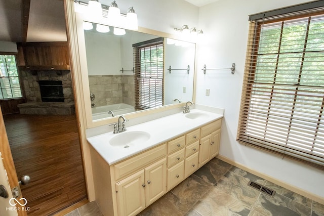 5530 Shawnee Trail S Drive, Indianapolis, IN 46220 - bathroom featuring a stone fireplace, double vanity, a bath, and plenty of natural light