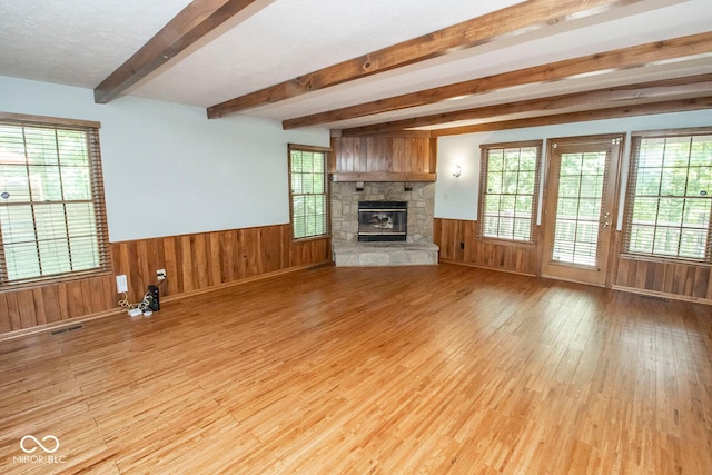 5530 Shawnee Trail S Drive, Indianapolis, IN 46220 - unfurnished living room with light wood-style flooring, beamed ceiling, wainscoting, a stone fireplace, and wooden walls