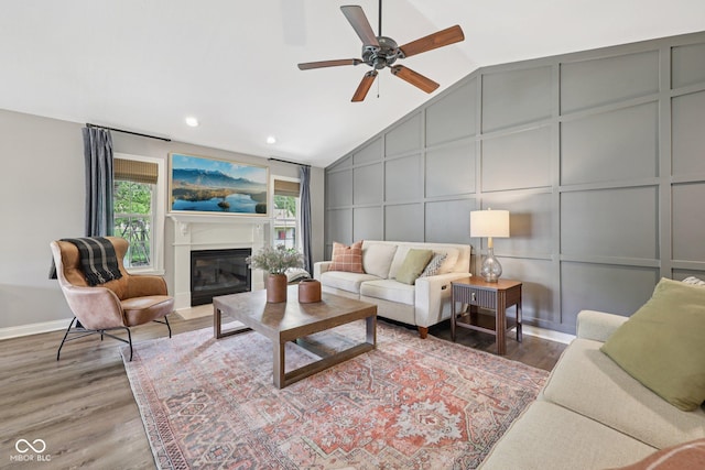 3571 S Cedar Creek Ln, New Palestine, IN 46163 - living area with a decorative wall, vaulted ceiling, wood finished floors, ceiling fan, and a glass covered fireplace