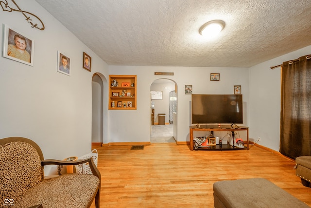 450 Columbia Ave, Tipton, IN 46072 - living area featuring arched walkways, a textured ceiling, wood finished floors, built in features, and baseboards