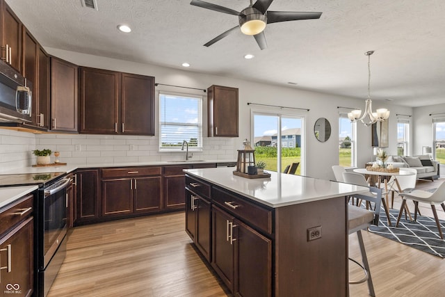 10112 Gallop Ln, Fishers, IN 46040 - kitchen with stainless steel appliances, a kitchen bar, light wood-type flooring, a chandelier, and recessed lighting