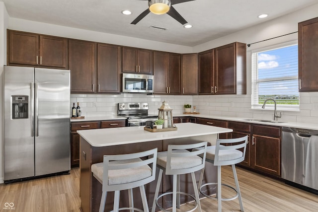 10112 Gallop Ln, Fishers, IN 46040 - kitchen with appliances with stainless steel finishes, a kitchen breakfast bar, light wood finished floors, dark brown cabinets, and recessed lighting