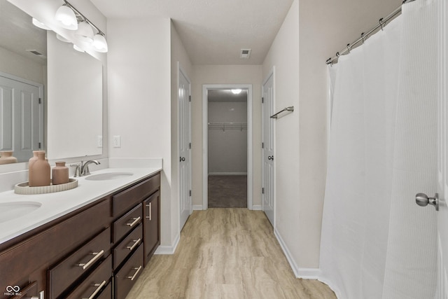 10112 Gallop Ln, Fishers, IN 46040 - bathroom featuring double vanity, a spacious closet, curtained shower, and wood finished floors