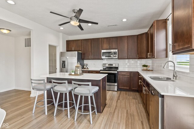 10112 Gallop Ln, Fishers, IN 46040 - kitchen with appliances with stainless steel finishes, light wood finished floors, a breakfast bar, tasteful backsplash, and recessed lighting
