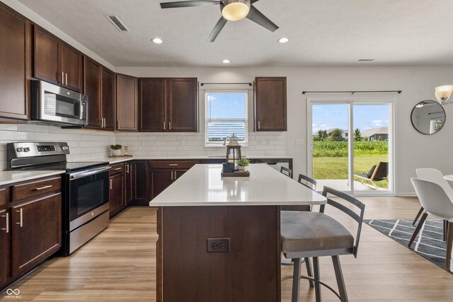 10112 Gallop Ln, Fishers, IN 46040 - kitchen with stainless steel appliances, a breakfast bar, backsplash, light wood-style floors, and recessed lighting
