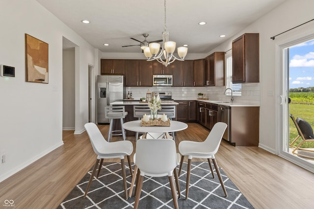 10112 Gallop Ln, Fishers, IN 46040 - kitchen featuring stainless steel appliances, a kitchen island, backsplash, light wood-style floors, and a chandelier