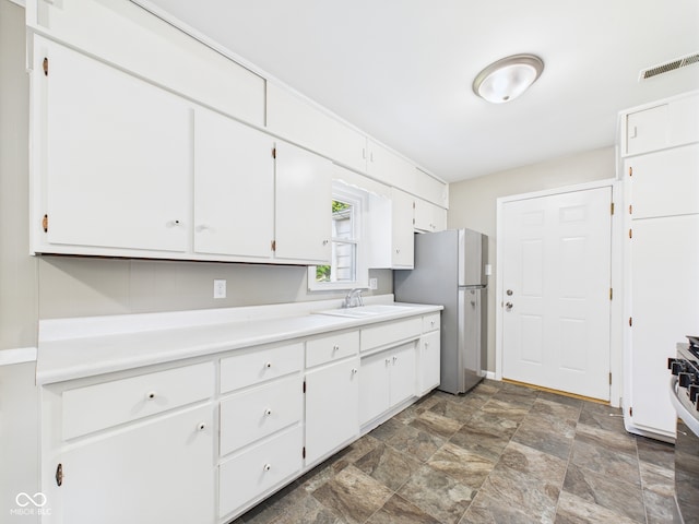 220 Central Ave, Anderson, IN 46012 - kitchen with freestanding refrigerator, white cabinets, stone finish floors, a sink, and light countertops