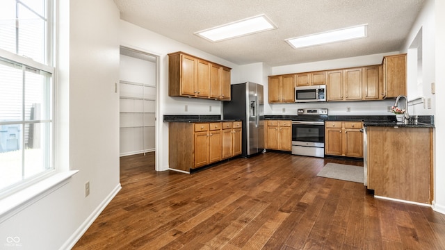 10216 Hatherley Way, Fishers, IN 46037 - kitchen with appliances with stainless steel finishes, dark wood-type flooring, dark countertops, a textured ceiling, and brown cabinetry