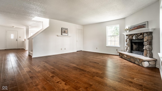 10216 Hatherley Way, Fishers, IN 46037 - unfurnished living room featuring a textured ceiling, dark wood-style flooring, and a stone fireplace