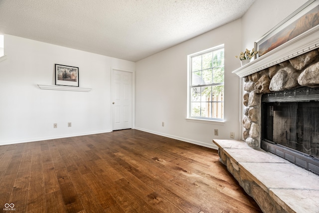 10216 Hatherley Way, Fishers, IN 46037 - unfurnished living room with hardwood / wood-style flooring, a stone fireplace, and a textured ceiling