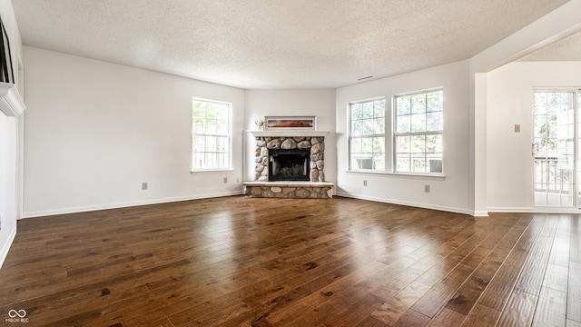10216 Hatherley Way, Fishers, IN 46037 - unfurnished living room featuring a textured ceiling, dark wood-type flooring, plenty of natural light, and a stone fireplace