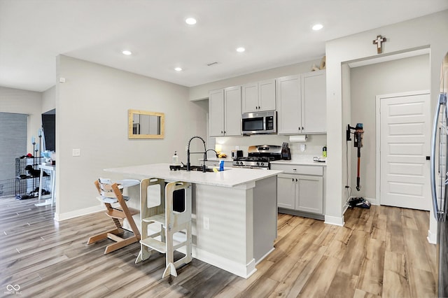 741 Scarsdale Ln, Danville, IN 46122 - kitchen featuring appliances with stainless steel finishes, a center island with sink, light wood finished floors, light countertops, and recessed lighting