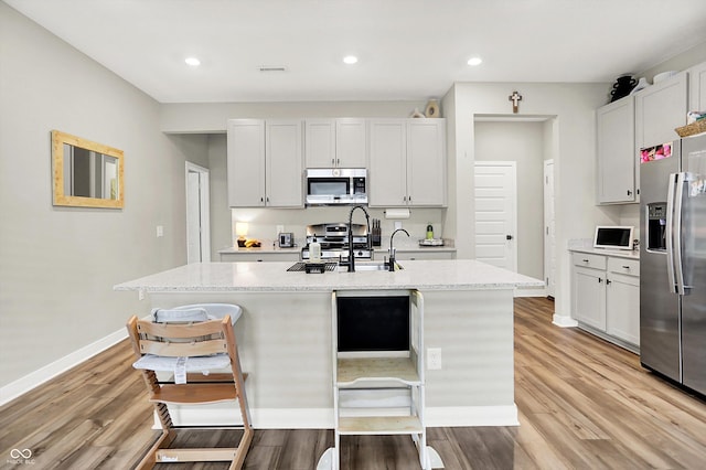 741 Scarsdale Ln, Danville, IN 46122 - kitchen with appliances with stainless steel finishes, an island with sink, light wood-type flooring, recessed lighting, and a kitchen bar