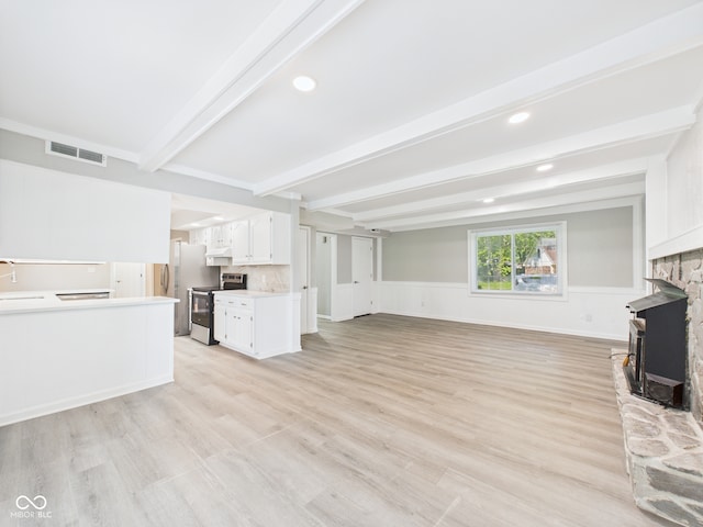 2126 Tartan Rd, Anderson, IN 46012 - unfurnished living room featuring beamed ceiling, light wood-type flooring, a stone fireplace, a wainscoted wall, and recessed lighting