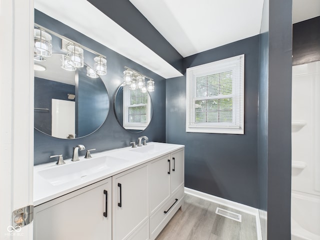2126 Tartan Rd, Anderson, IN 46012 - bathroom featuring double vanity, wood finished floors, vaulted ceiling, and bathing tub / shower combination