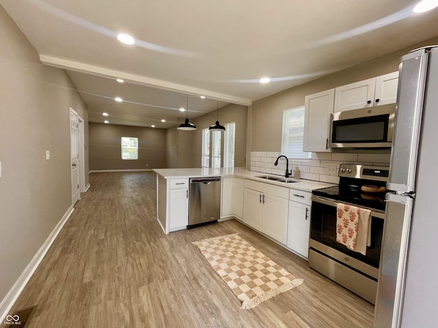 3835 N Kenwood Ave, Indianapolis, IN 46208 - kitchen featuring appliances with stainless steel finishes, a sink, light wood-style flooring, a peninsula, and white cabinets