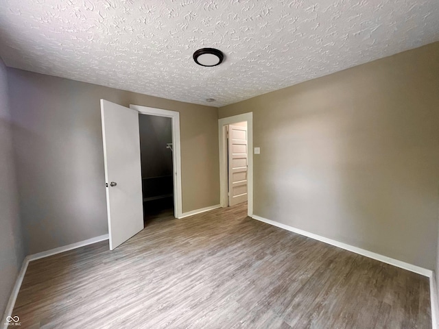 3835 N Kenwood Ave, Indianapolis, IN 46208 - unfurnished bedroom with wood finished floors, a textured ceiling, and baseboards