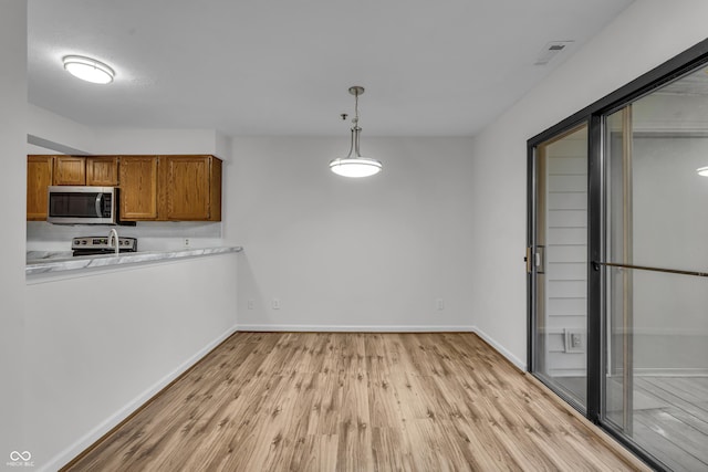 8176 Shorewalk Dr Unit C, Indianapolis, IN 46236 - kitchen with appliances with stainless steel finishes, brown cabinets, light wood-style flooring, light countertops, and hanging light fixtures